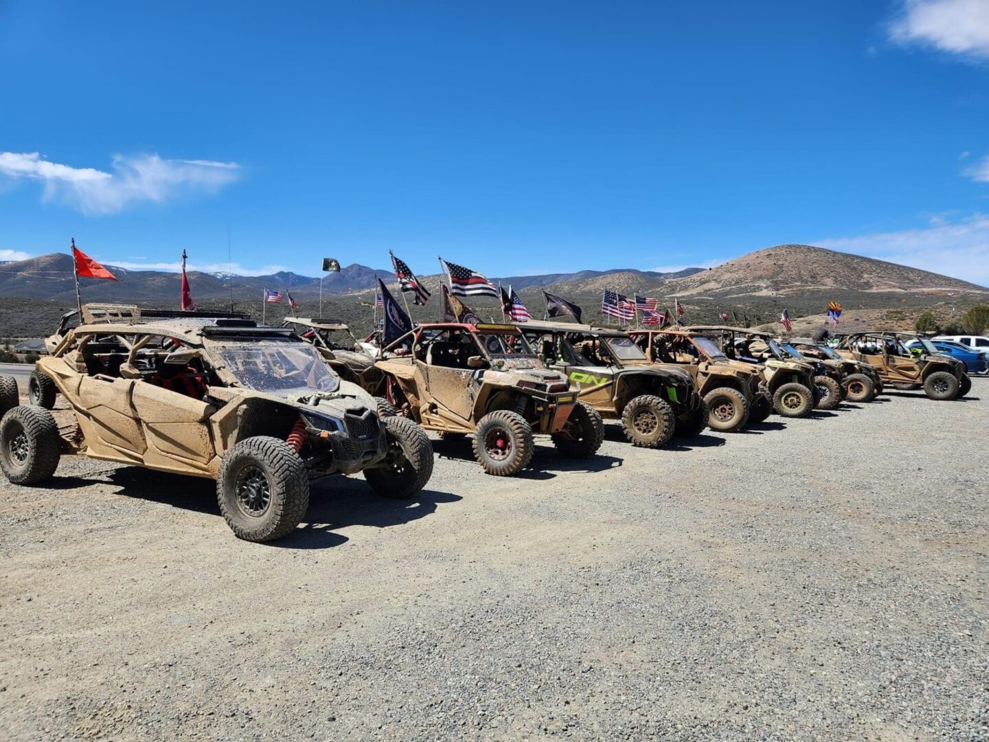 A row of parked off road vehicles on the side of a dirt road.