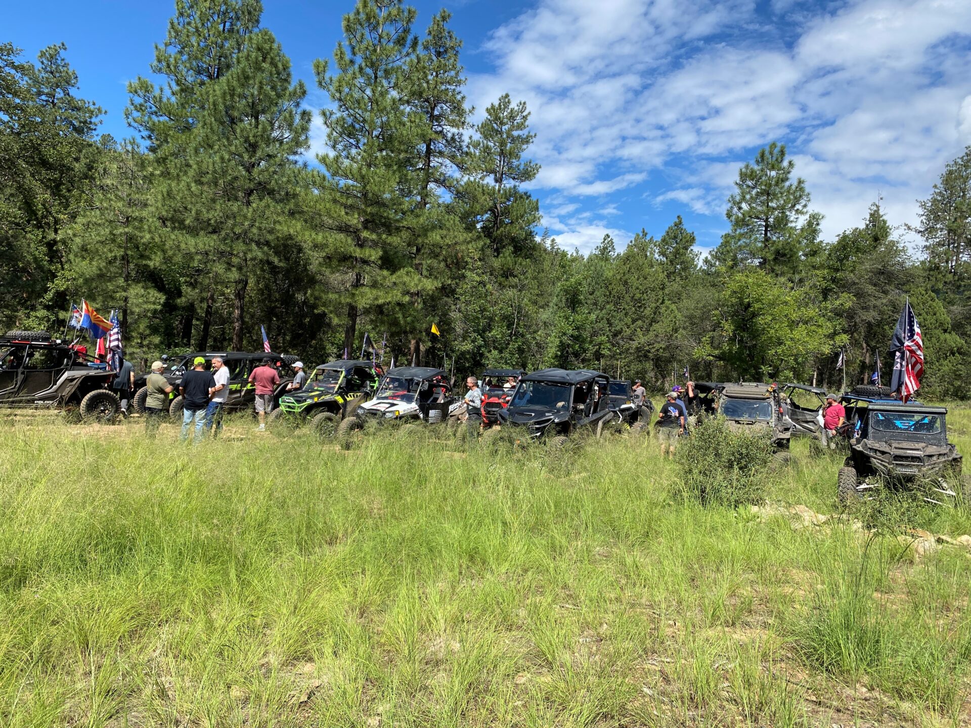 A group of people standing around in the grass.