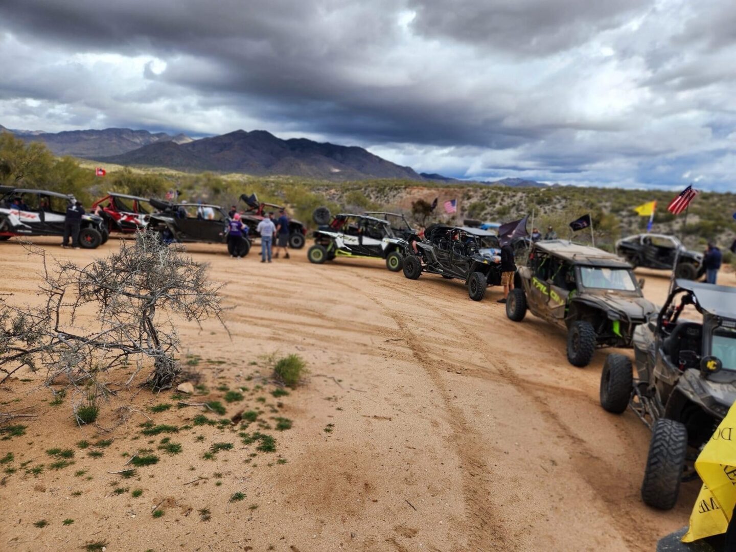 A group of off road vehicles parked on the side of a dirt road.