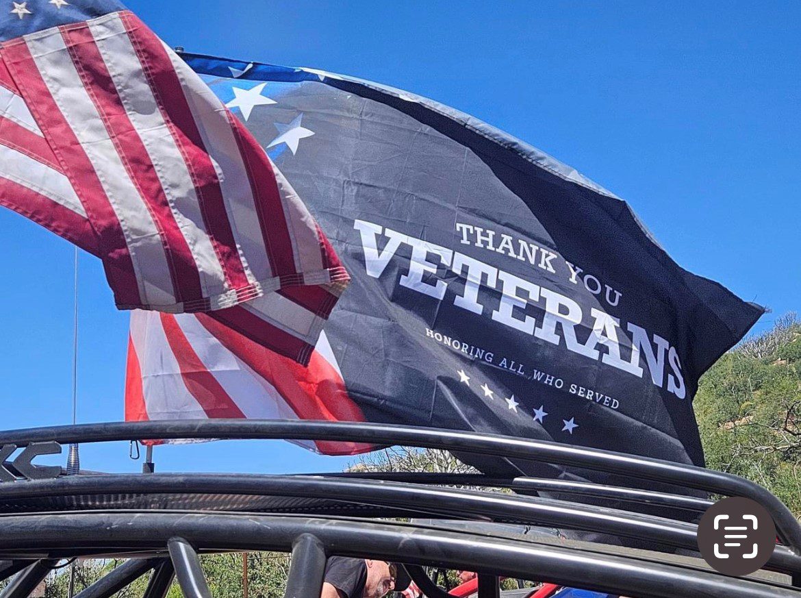 A close up of two flags on top of a metal fence.