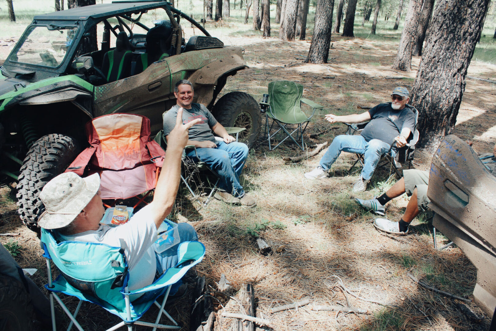 A group of people sitting in the woods with their camping chairs.