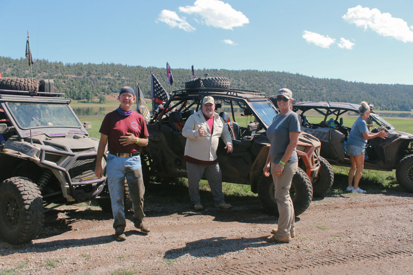 Three men standing next to a bunch of parked off road vehicles.