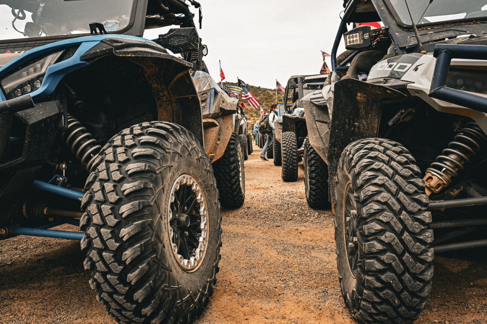 A group of four off road vehicles parked on top of dirt.