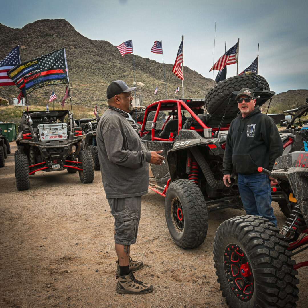 Two men standing next to a row of parked off road vehicles.