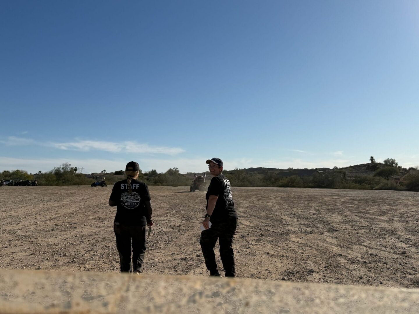 Two staff walking across open dry field