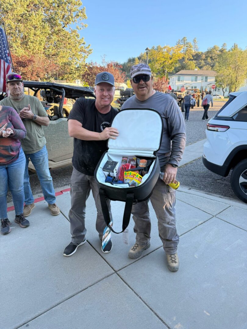 Two men holding open cooler with snacks