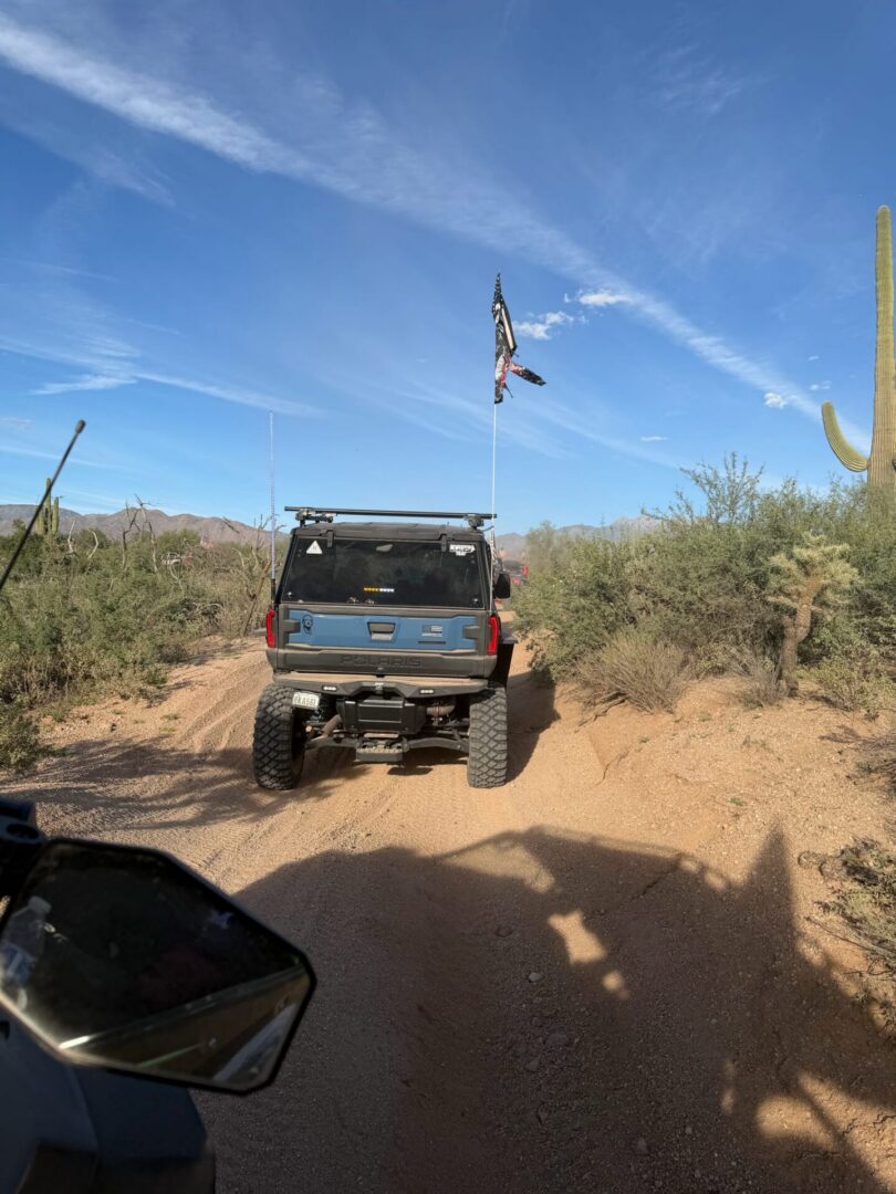 Lifted SUV off-roading on desert trail with flag