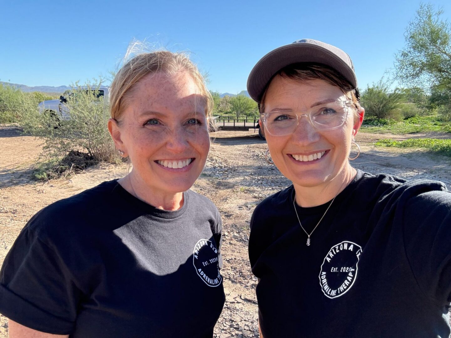 Two smiling women wearing matching black shirts