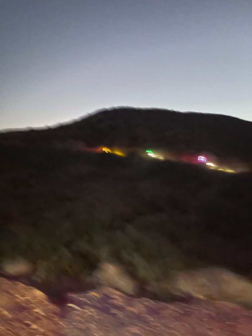 Distant colorful vehicle lights along dark hillside