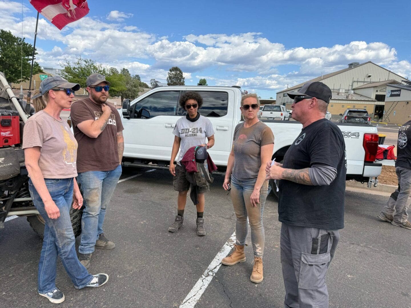 Five people standing by pickup trucks outdoors