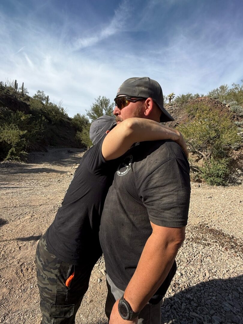 Two men embracing on rocky desert trail
