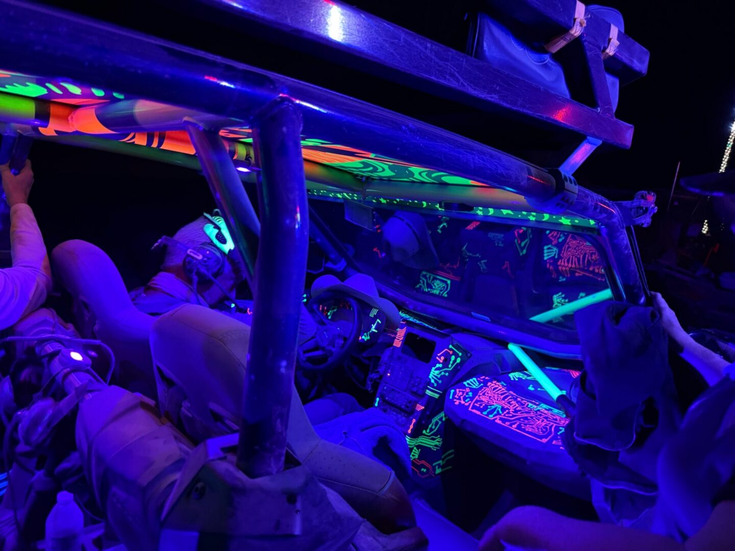 Neon-lit off-road vehicle interior with passengers