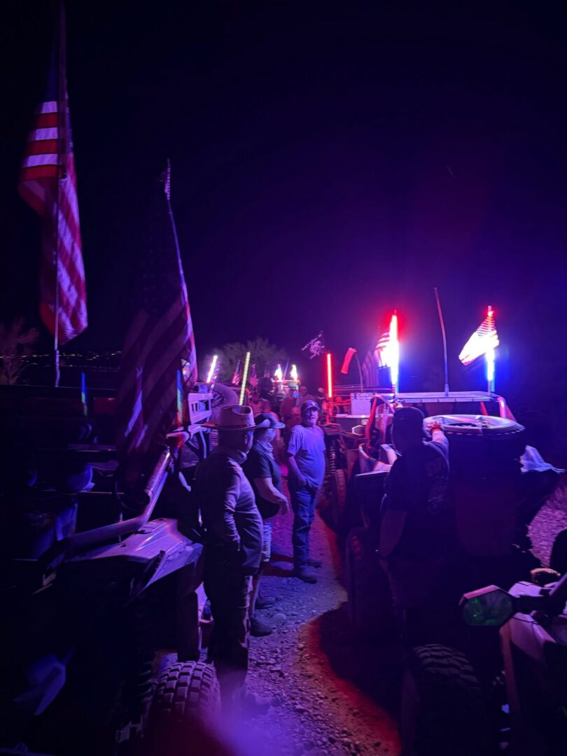 Nighttime off-road vehicle gathering with American flags