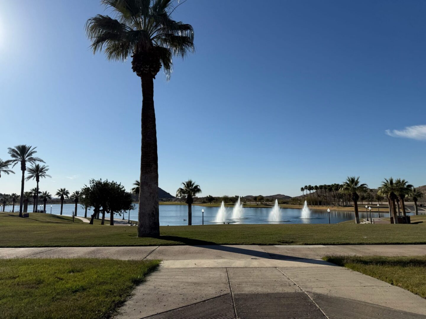Park pathway leading to lake with fountains