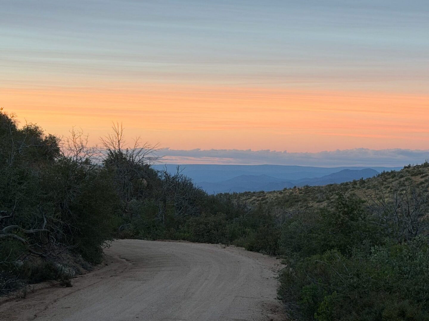 Winding dirt road at sunset with distant mountains