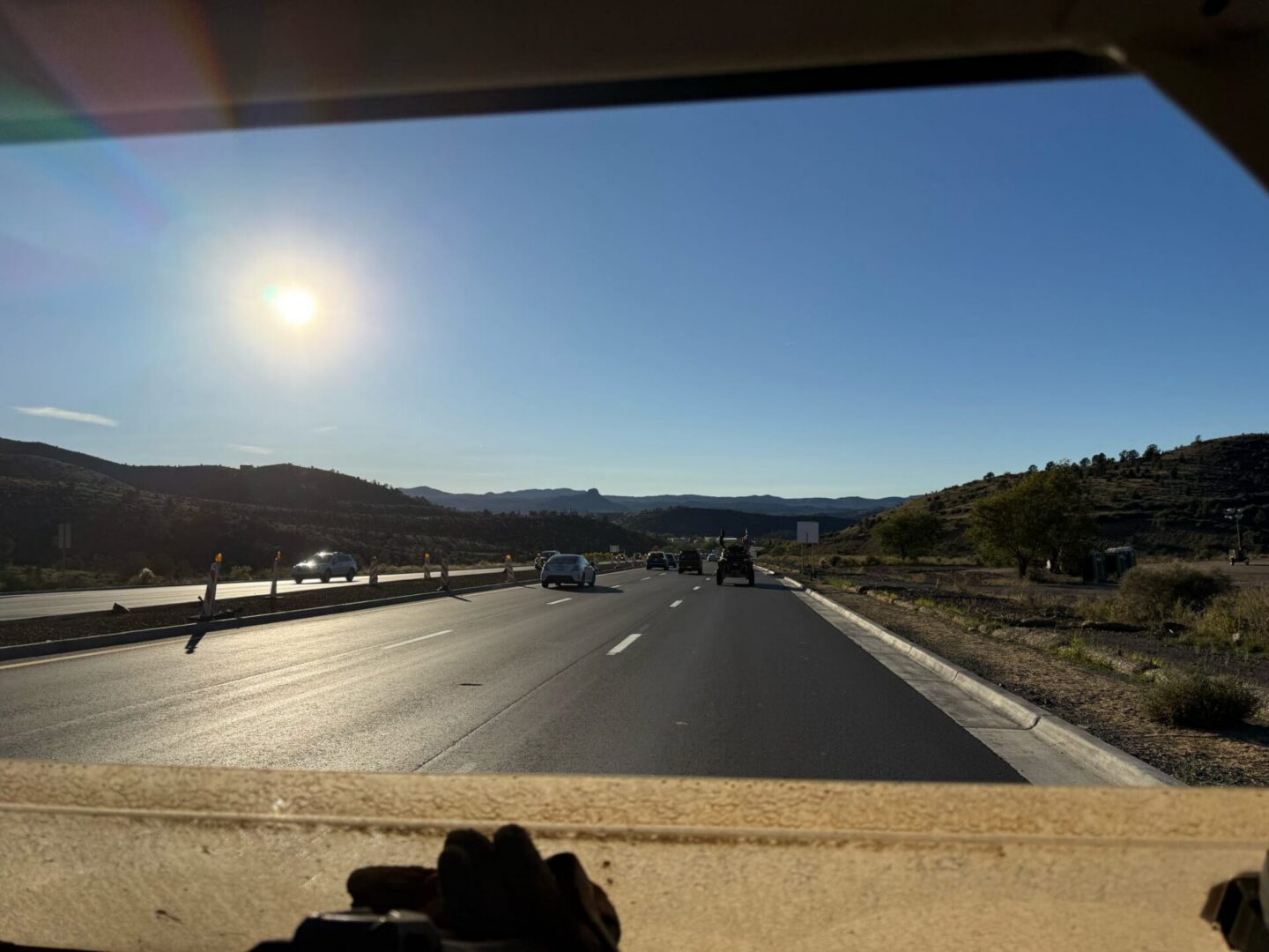 Sunlit highway through windshield with distant hills