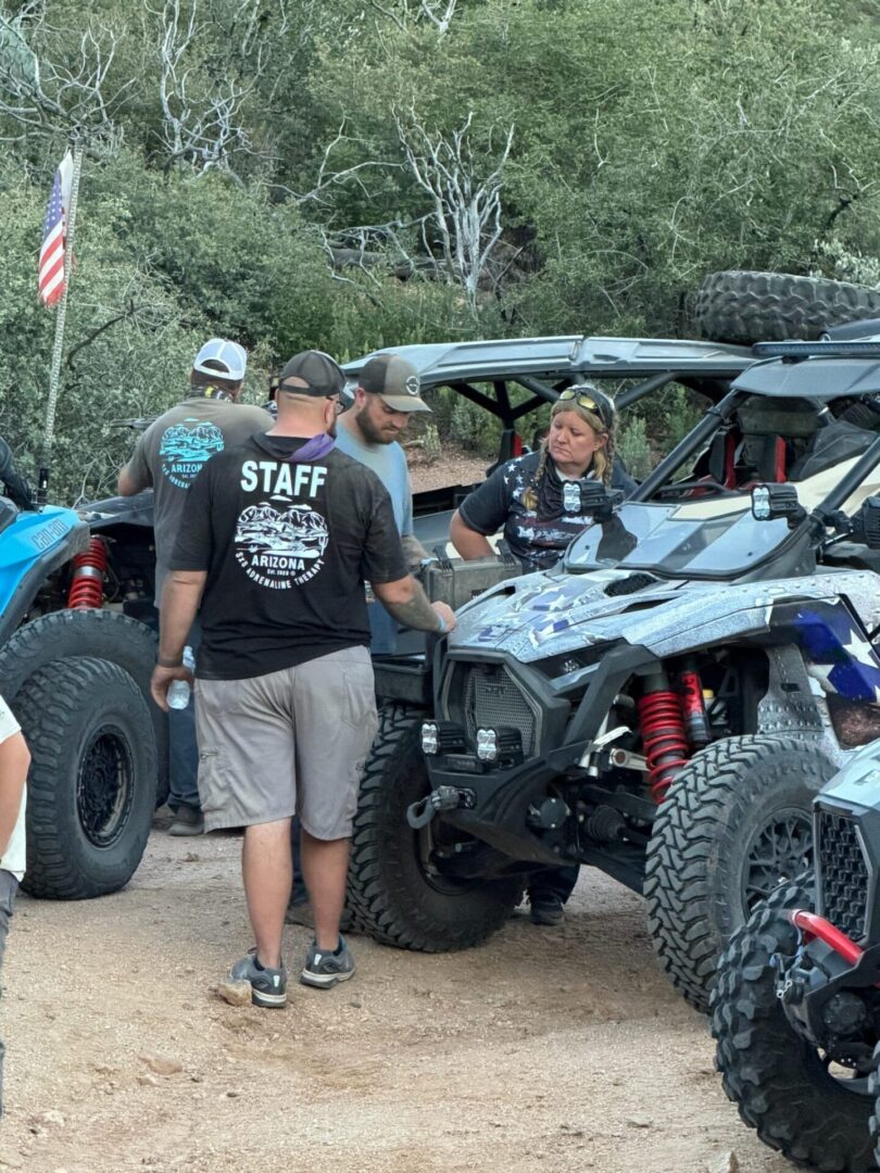 Group inspecting off-road UTVs on dirt trail
