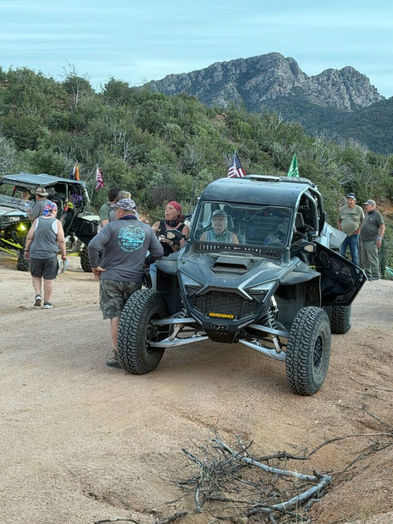Side-by-side UTVs and people on mountain trail