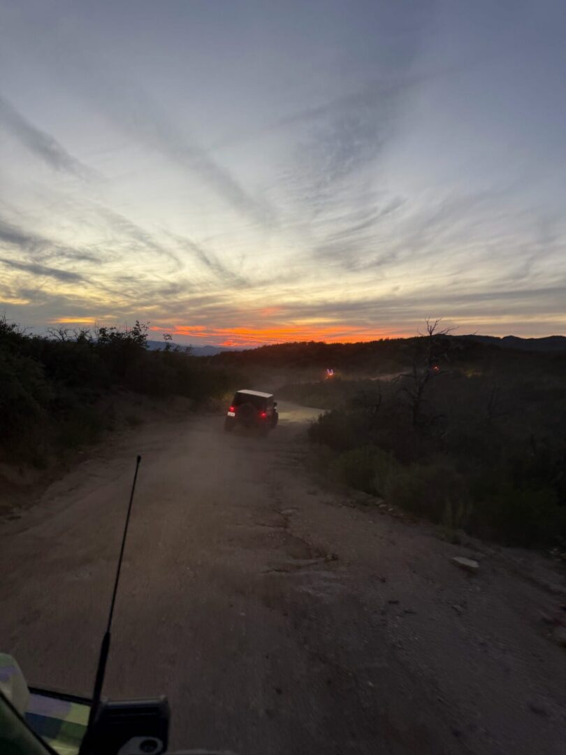 Vehicle on dusty dirt road at sunset