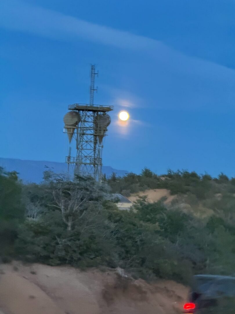 Communication tower at dusk with rising moon