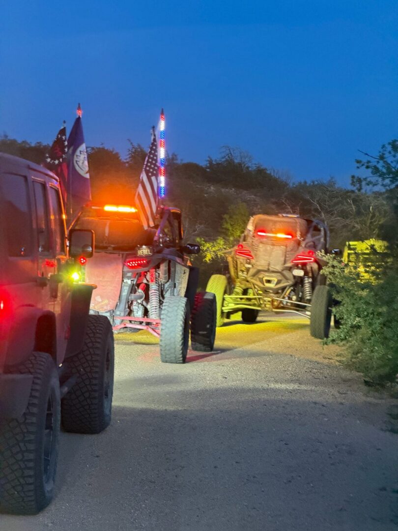 UTVs with flags and lights on dirt road
