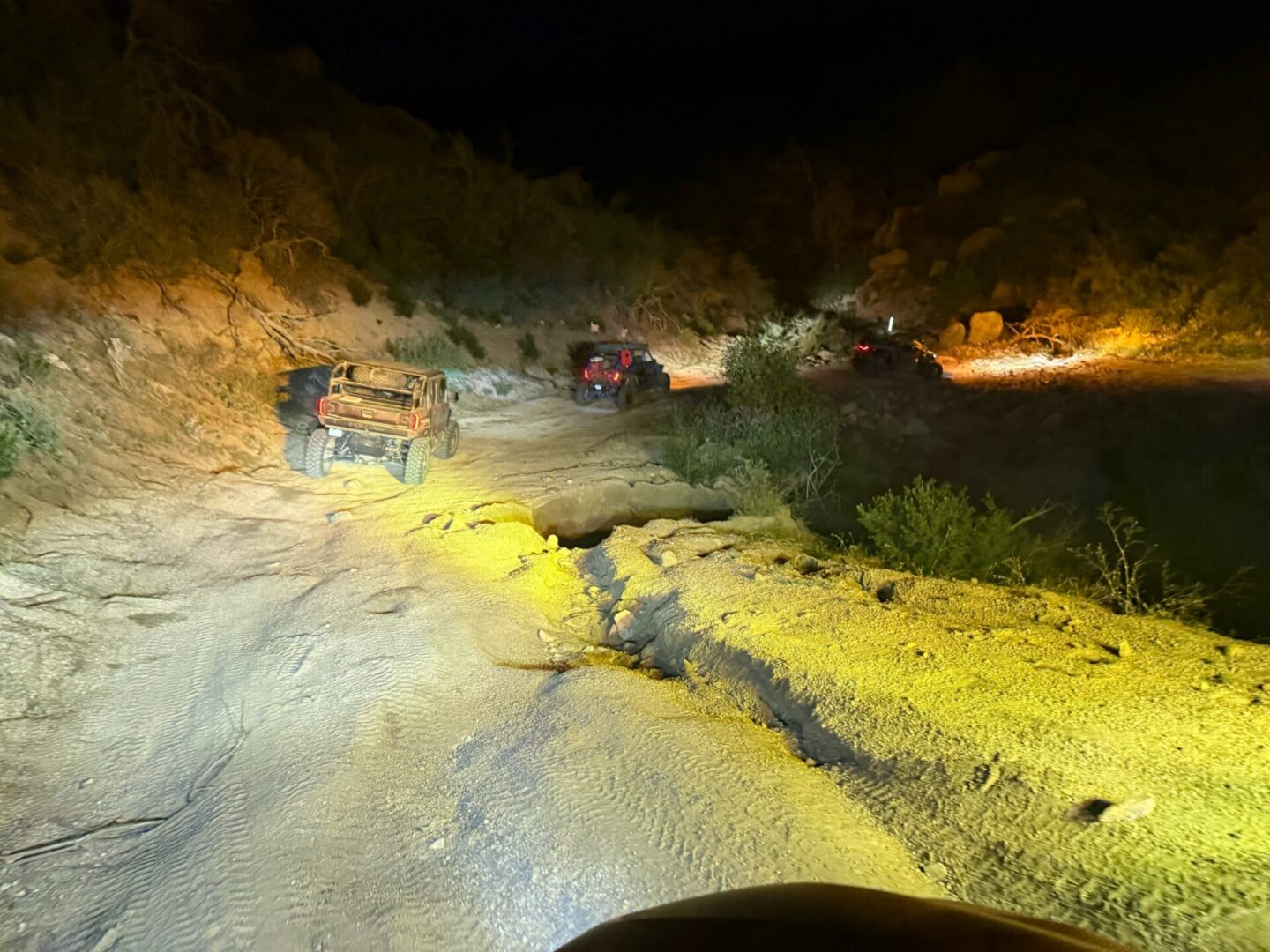 Nighttime off-road vehicles on rocky dirt trail