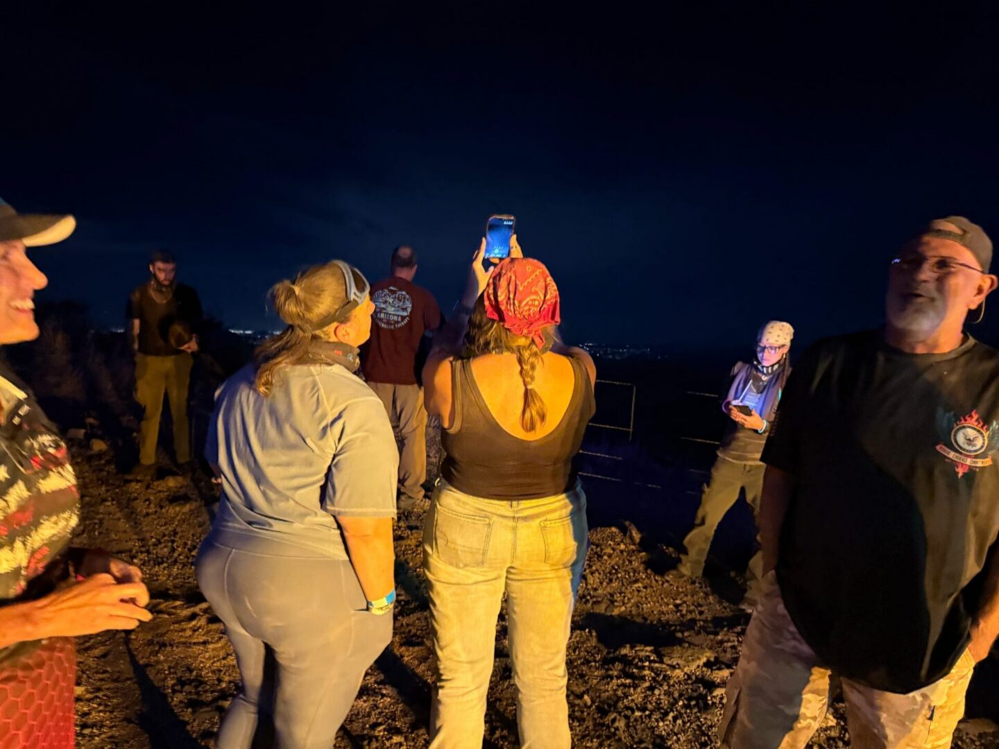 Group on hilltop at night, woman filming