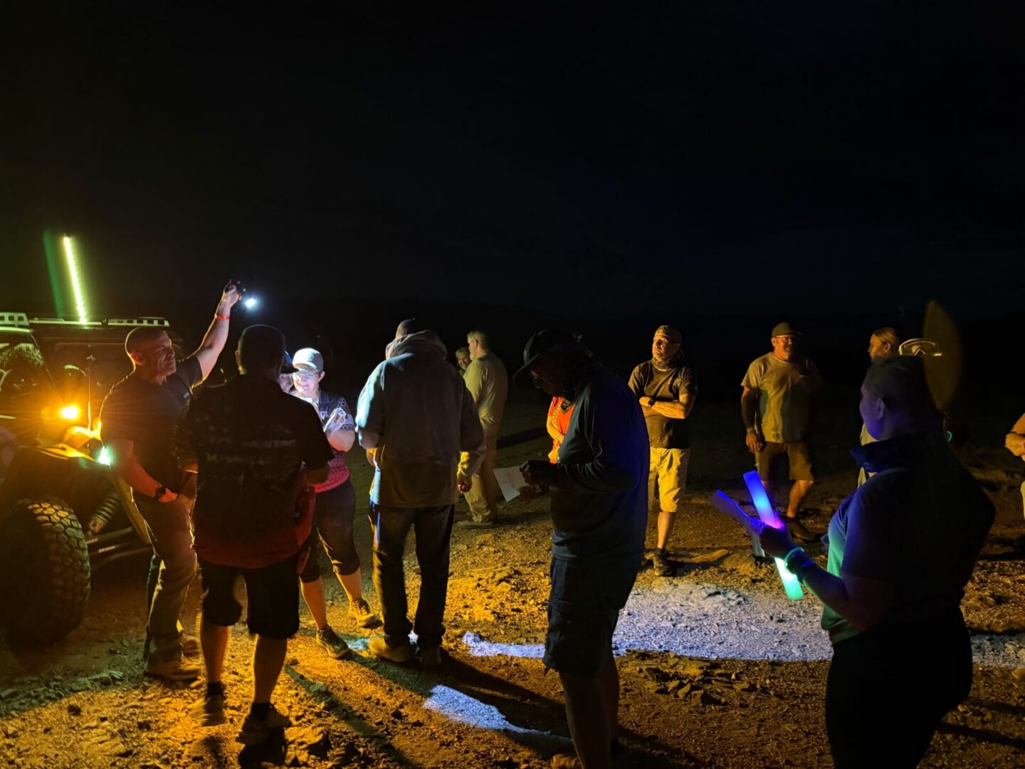 Group of people gathered at night near vehicle