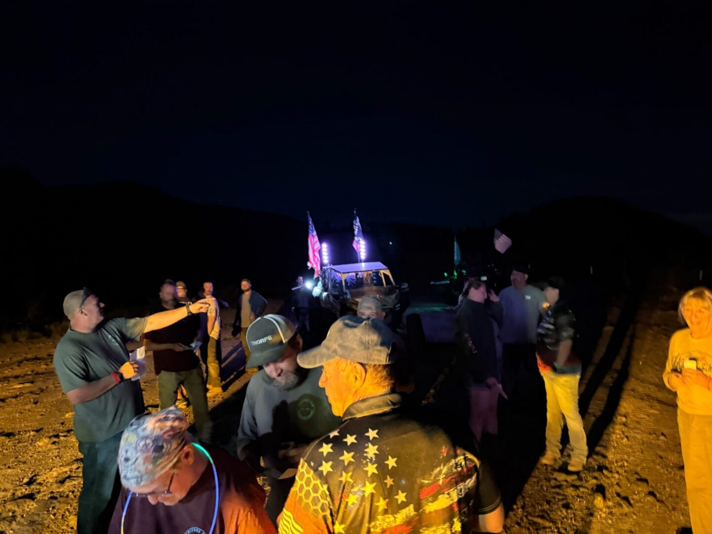 Nighttime outdoor gathering around truck with American flags
