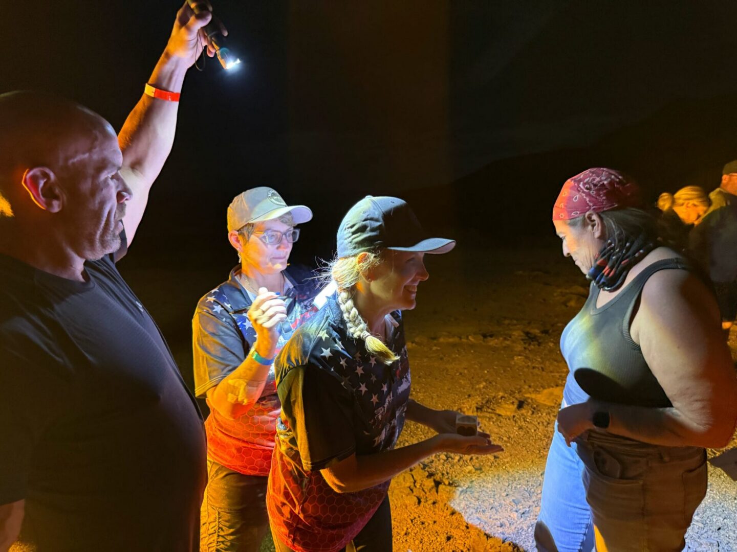 People gathered, lit by handheld light
