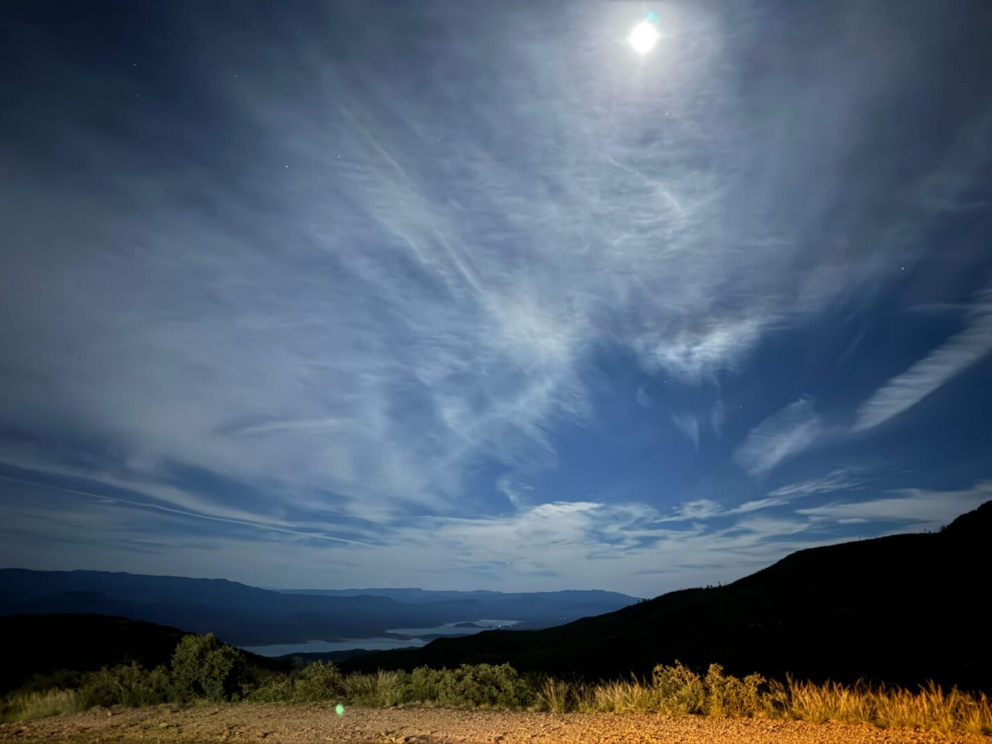 Moonlit mountain landscape with wispy clouds