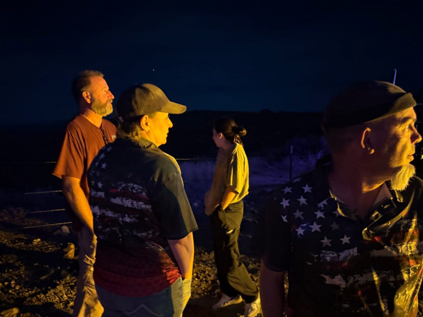 Four people standing outdoors at night