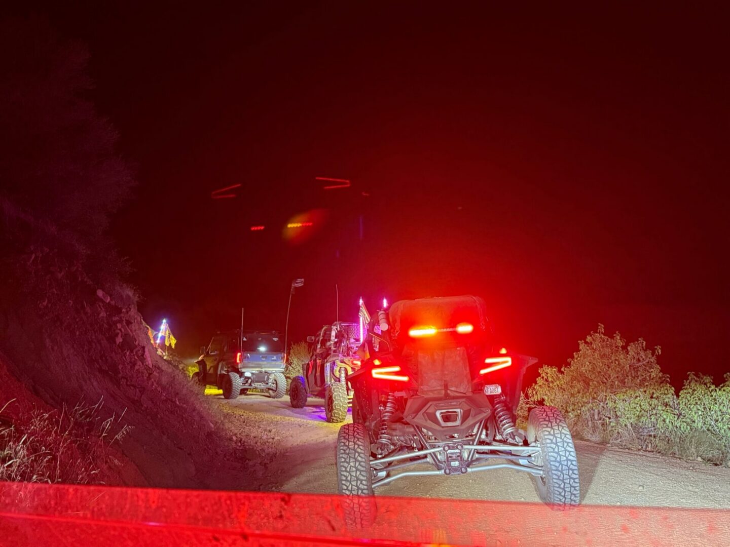 UTVs driving on dirt trail at night