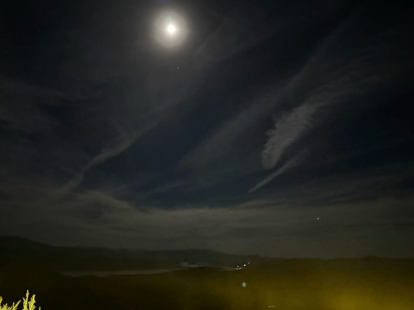 Moonlit landscape with clouds and distant lights