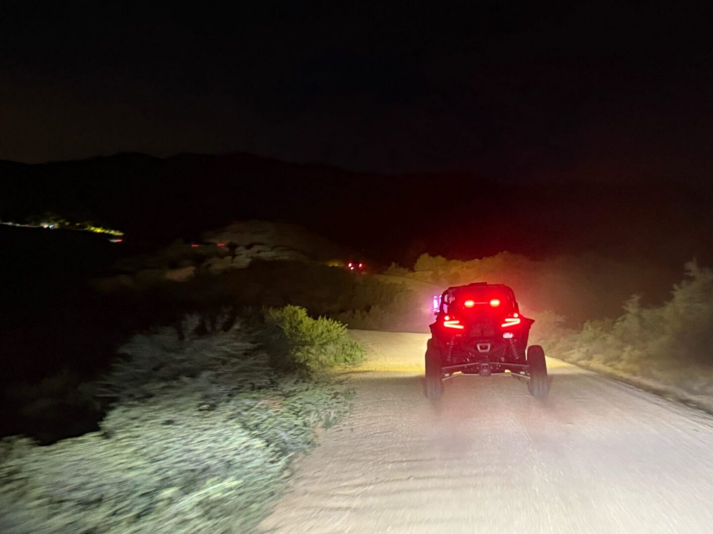 Off-road UTV with red taillights at night