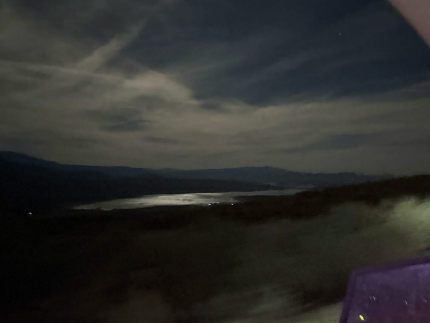 Moonlit lake with silhouetted hills and clouds