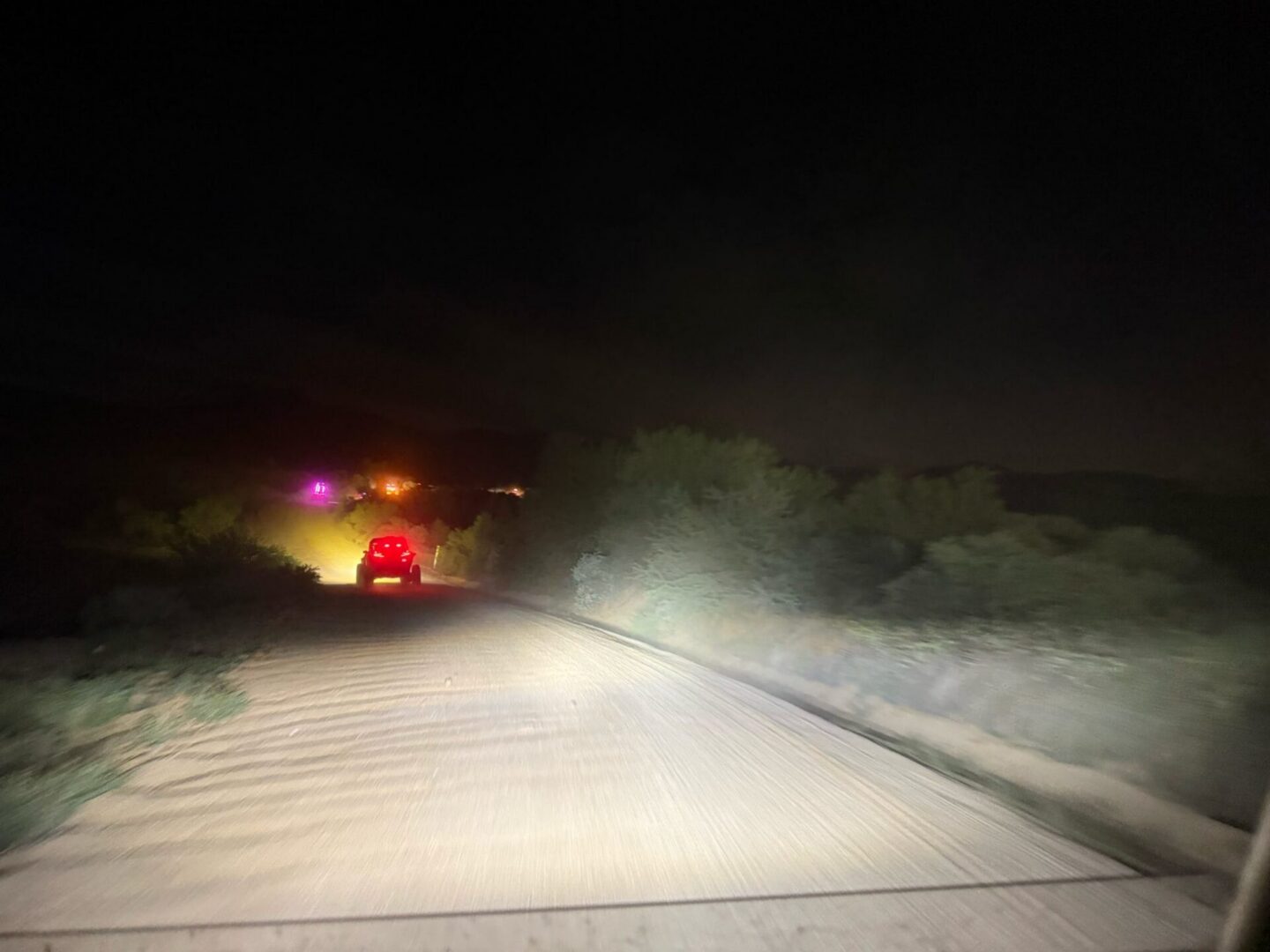 Car driving on dark dirt road at night