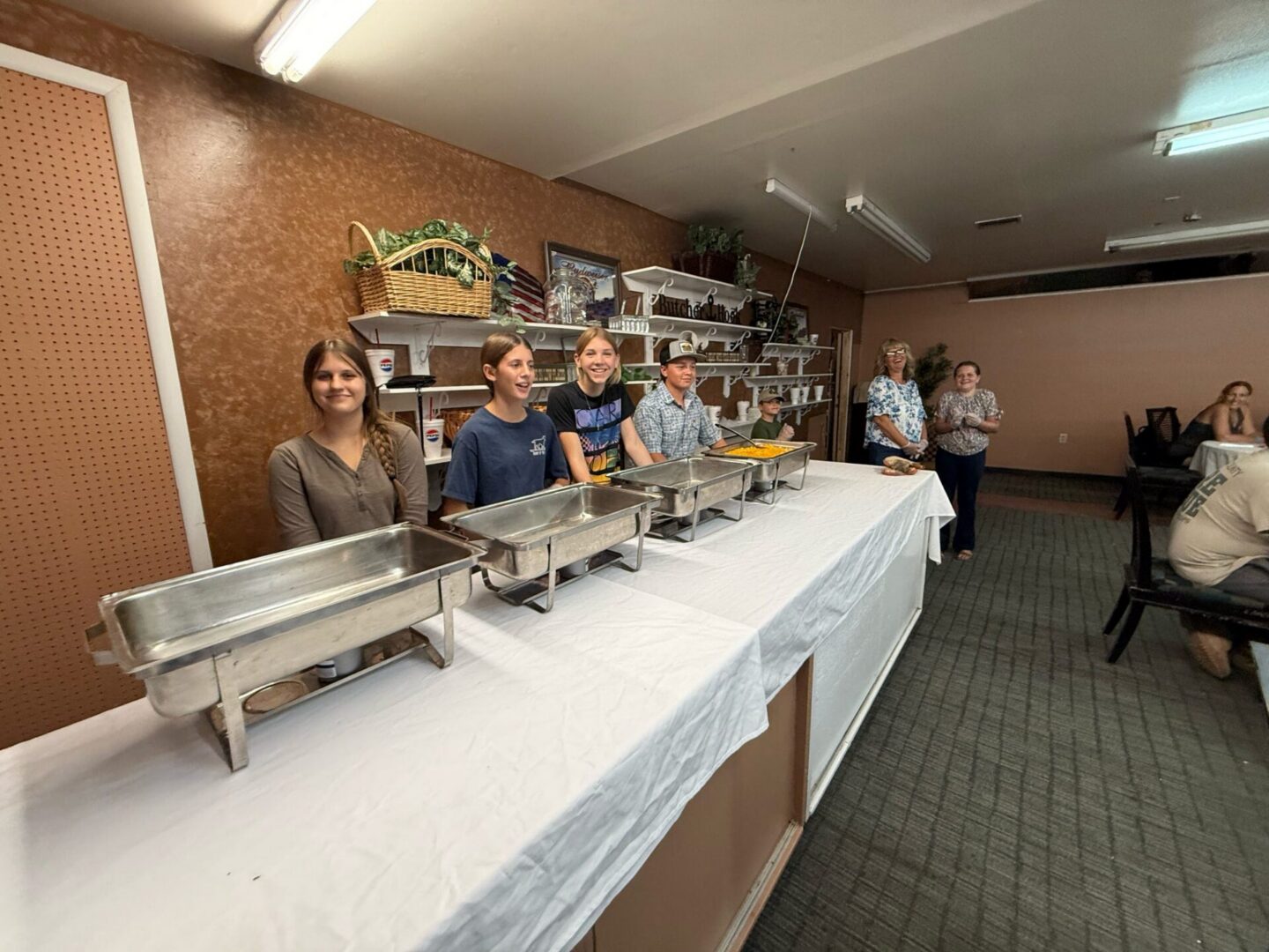 Volunteers standing behind buffet serving dishes