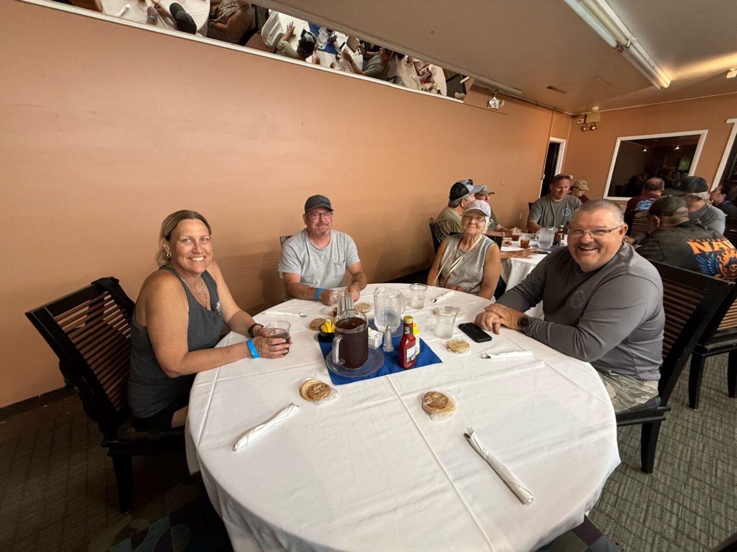 Four diners smiling around a round restaurant table