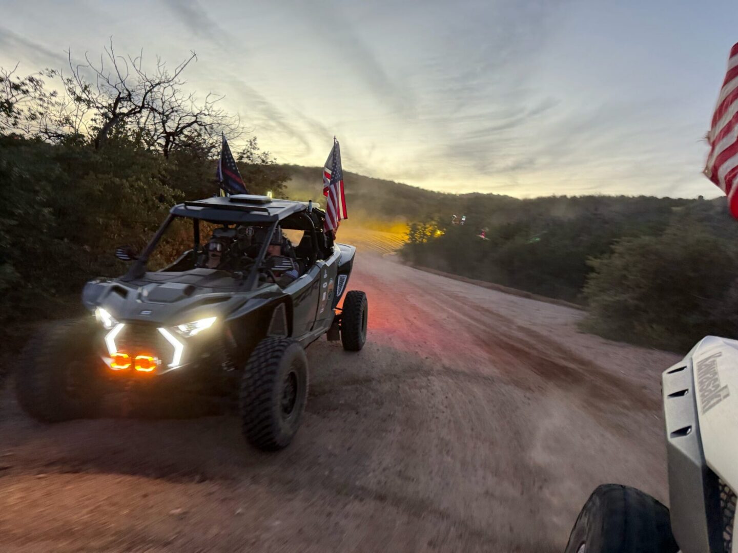 UTV with American flags on dirt trail