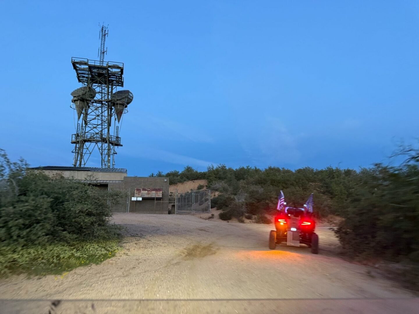 ATV driving toward communications tower at dusk