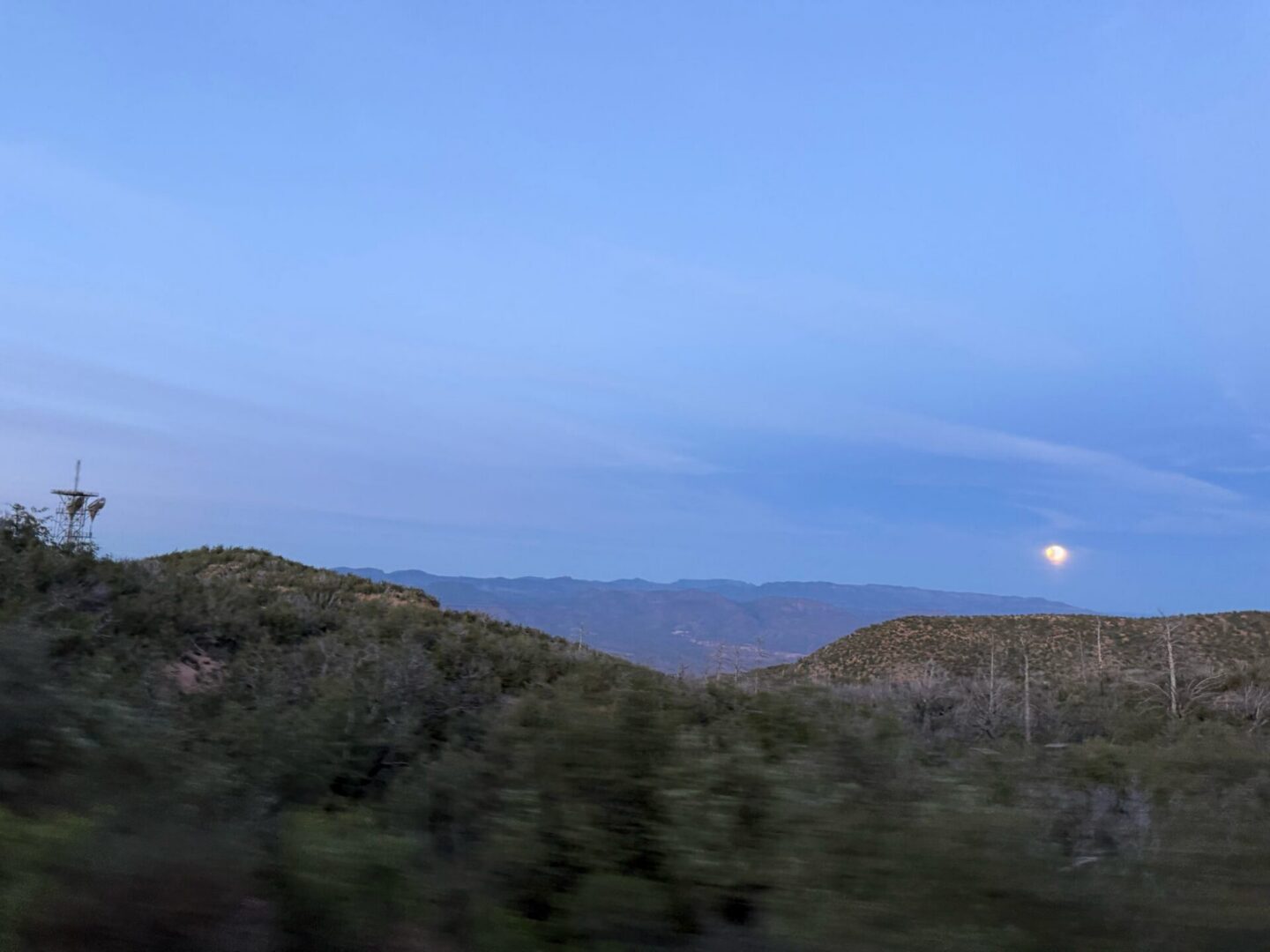 Moon rising over desert hills at twilight