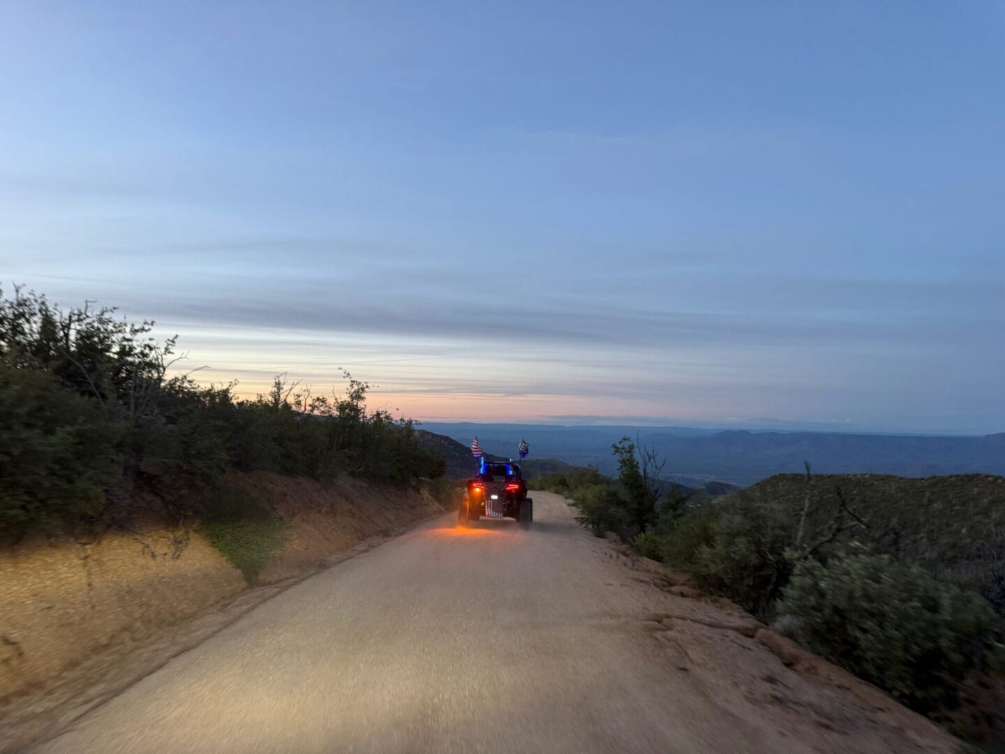 ATV driving on dirt road at sunset