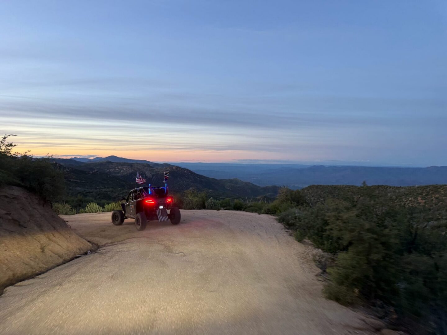 UTV with flags on dirt road at sunset