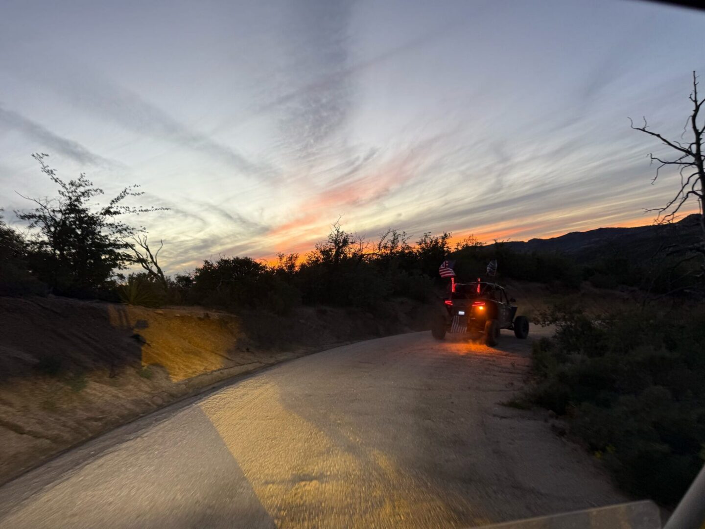 UTV driving on dirt road at sunset