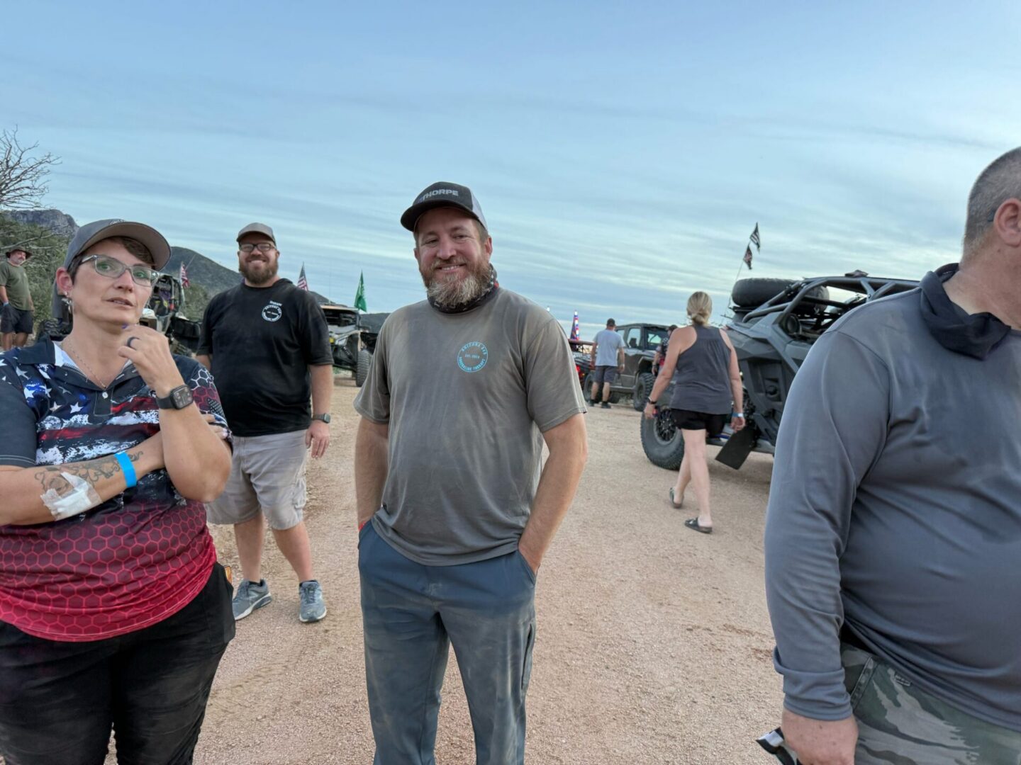 People gathered around off-road vehicles on dirt road