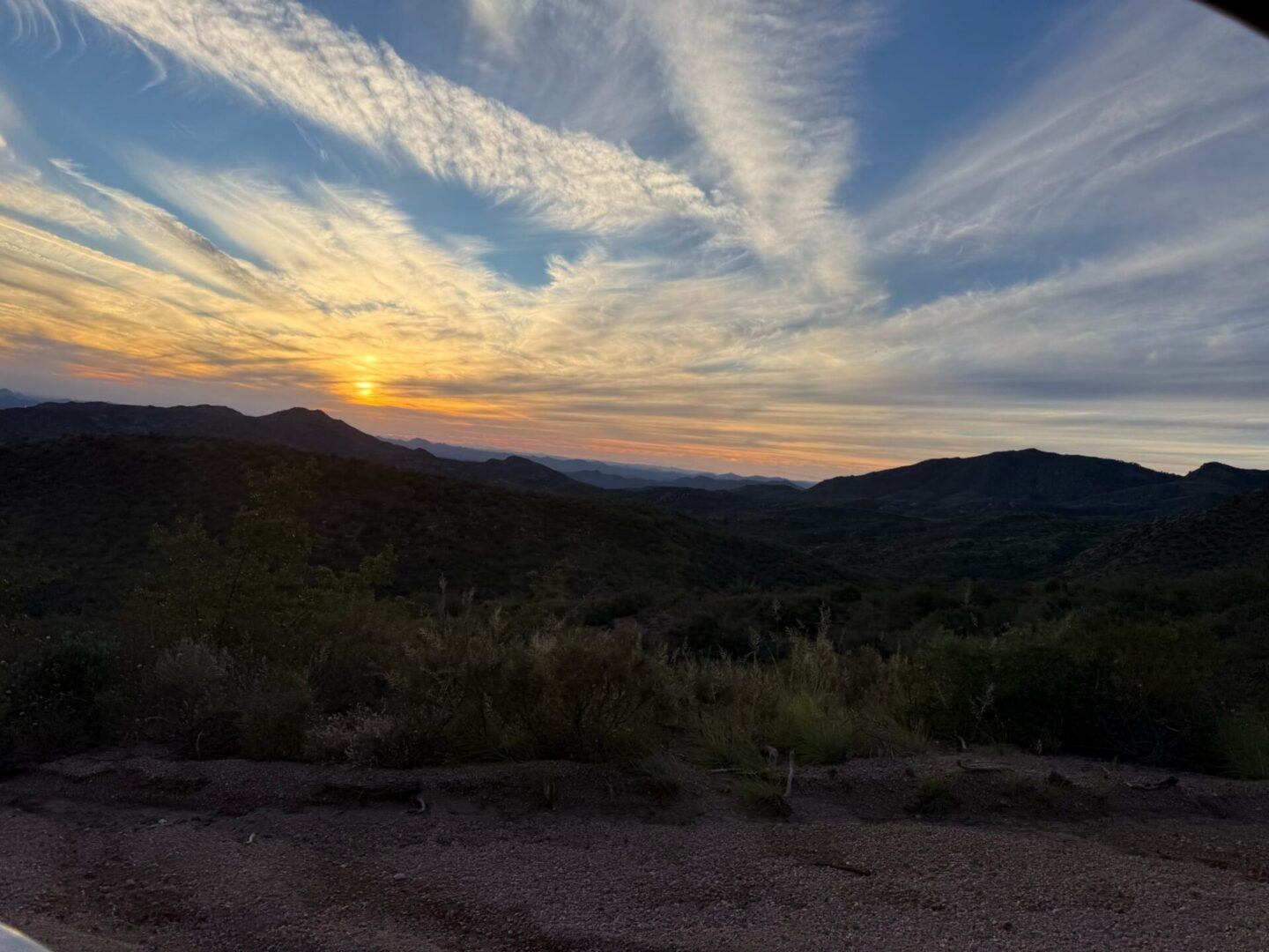 Sunset over rolling hills with streaked clouds