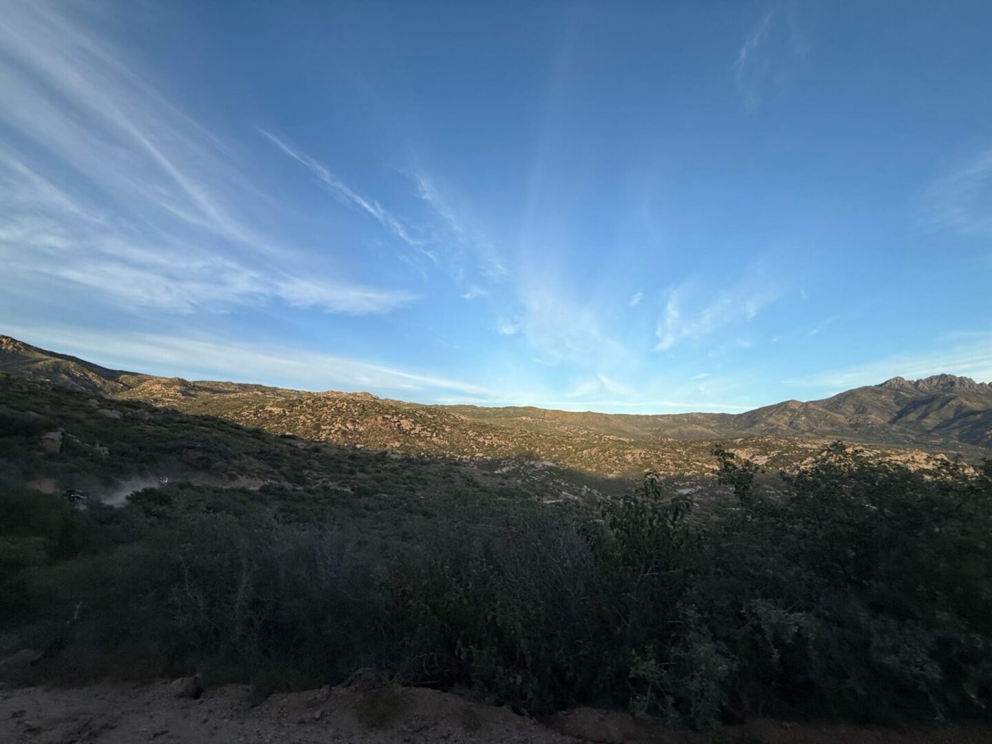 Sunlit desert hills under wispy blue sky