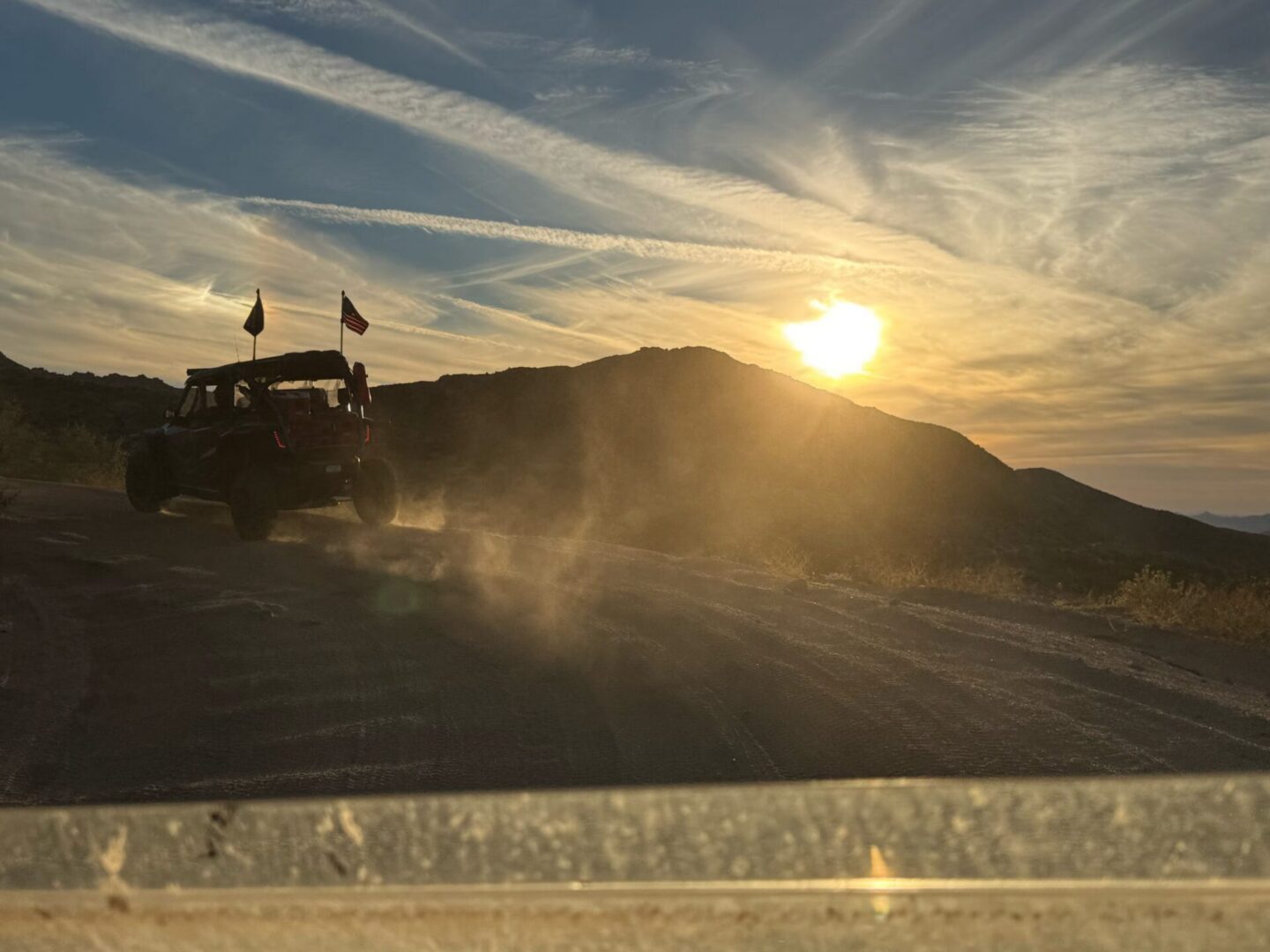 Off-road vehicle kicking up dust at sunset