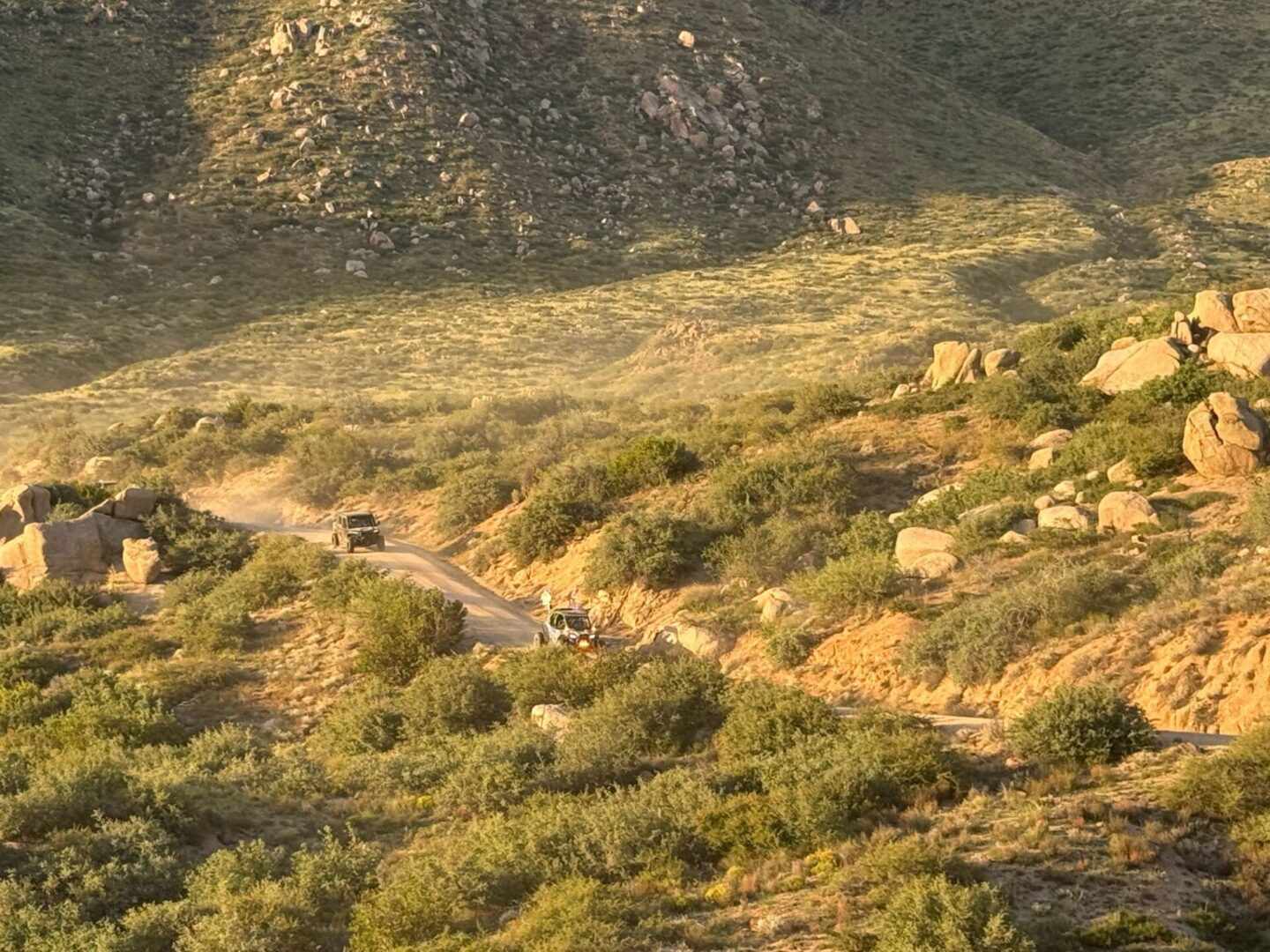 Off-road vehicles on winding hillside dirt road